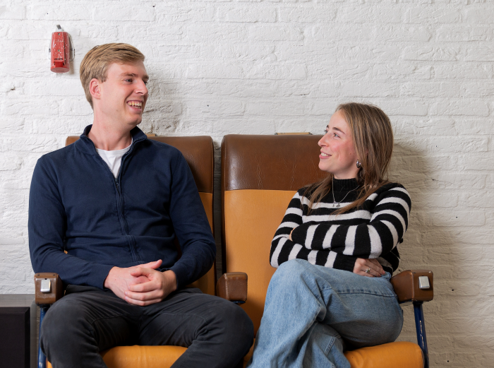 Ztorm trainees Tijn en Fleur zitten naast elkaar en kijken elkaar aan