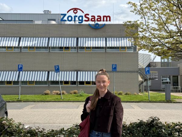 Young professional Iris voor het gebouw van Zorgsaam, haar opdrachtgever